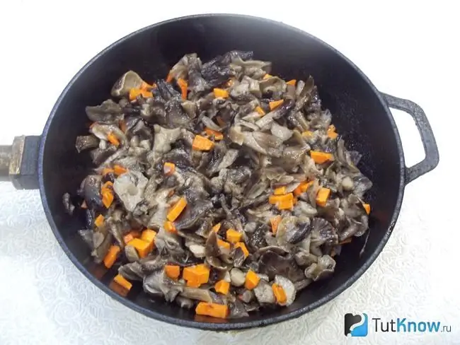 Mushrooms with carrots are fried in a pan