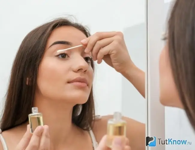 Woman applies argan oil to her eyelids