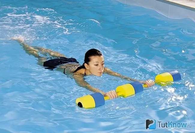 La noia treballa a la piscina amb peses especials