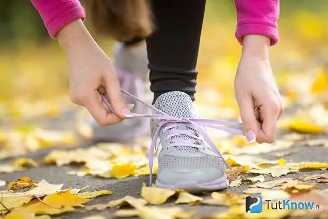 Flicka som knyter skosnören på sneakers innan hon springer