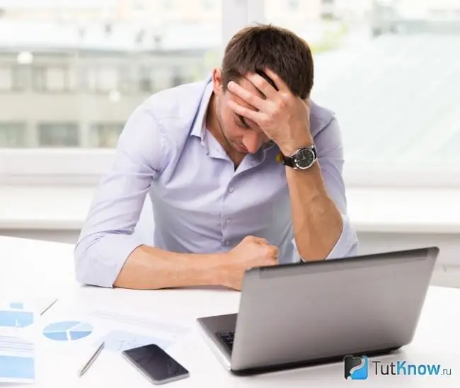 Um homem segurando sua cabeça sobre um computador