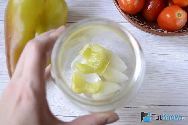 Slices of onions and bell peppers at the bottom of the jar