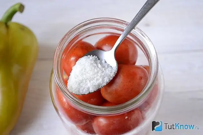 Una cucharada de sal sobre un frasco de tomates