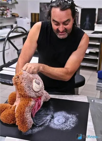 Un hombre imprime una imagen con un oso de peluche