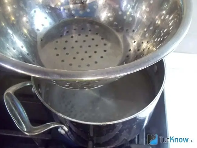 The sieve is placed on a pot of boiling water