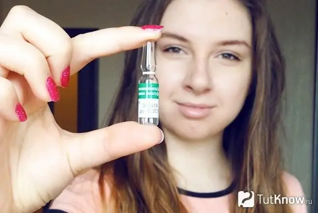 Menina segurando uma ampola com ácido nicotínico com dois dedos