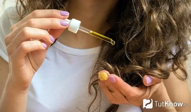 Chica goteando aceite de argán en su cabello