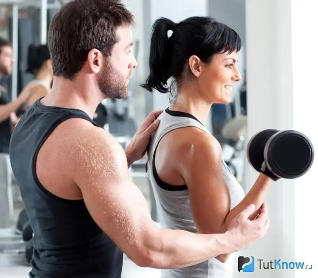 Frau trainiert im Fitnessstudio mit einem Trainer