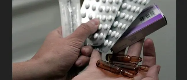 Man holds a plate with pills and ampoules in his hands