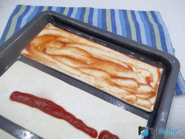 Ang kuwarta ay defrosted, inilatag sa isang baking sheet at greased na may ketchup