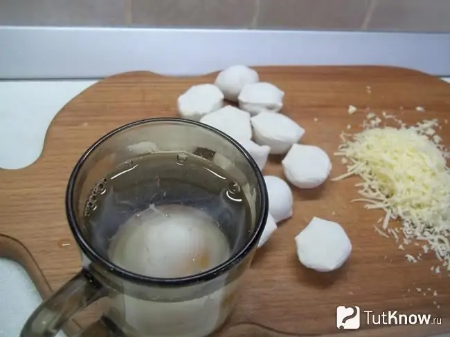 Un huevo escalfado se cocina en el microondas. Queso rallado