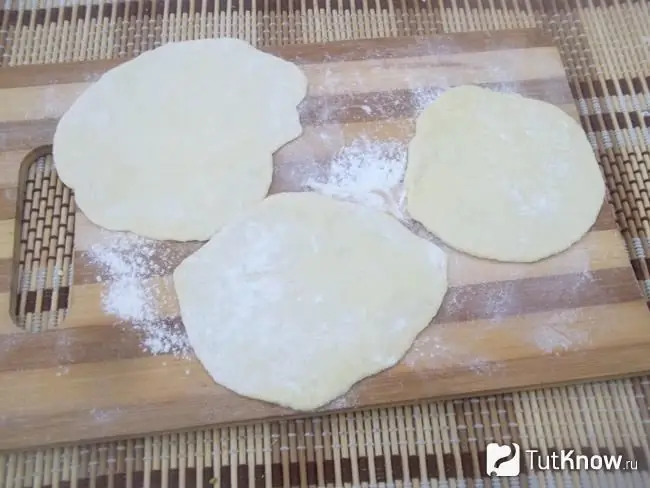 Morceaux de pâte pour boulettes aux cerises étalés avec un rouleau à pâtisserie